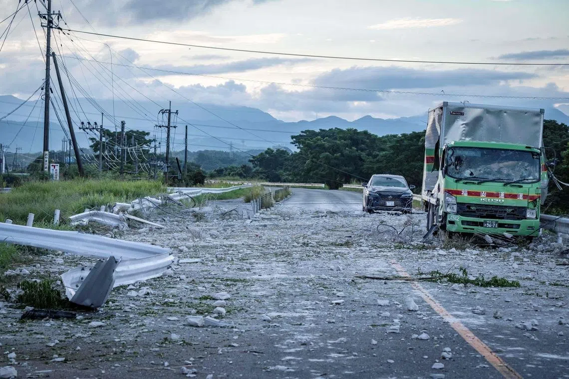 A damaged truck and car are seen on a debris-covered road following an explosion at the Aeon Mall Kumamoto in Kashima, Kumamoto Prefecture, on July 29.
