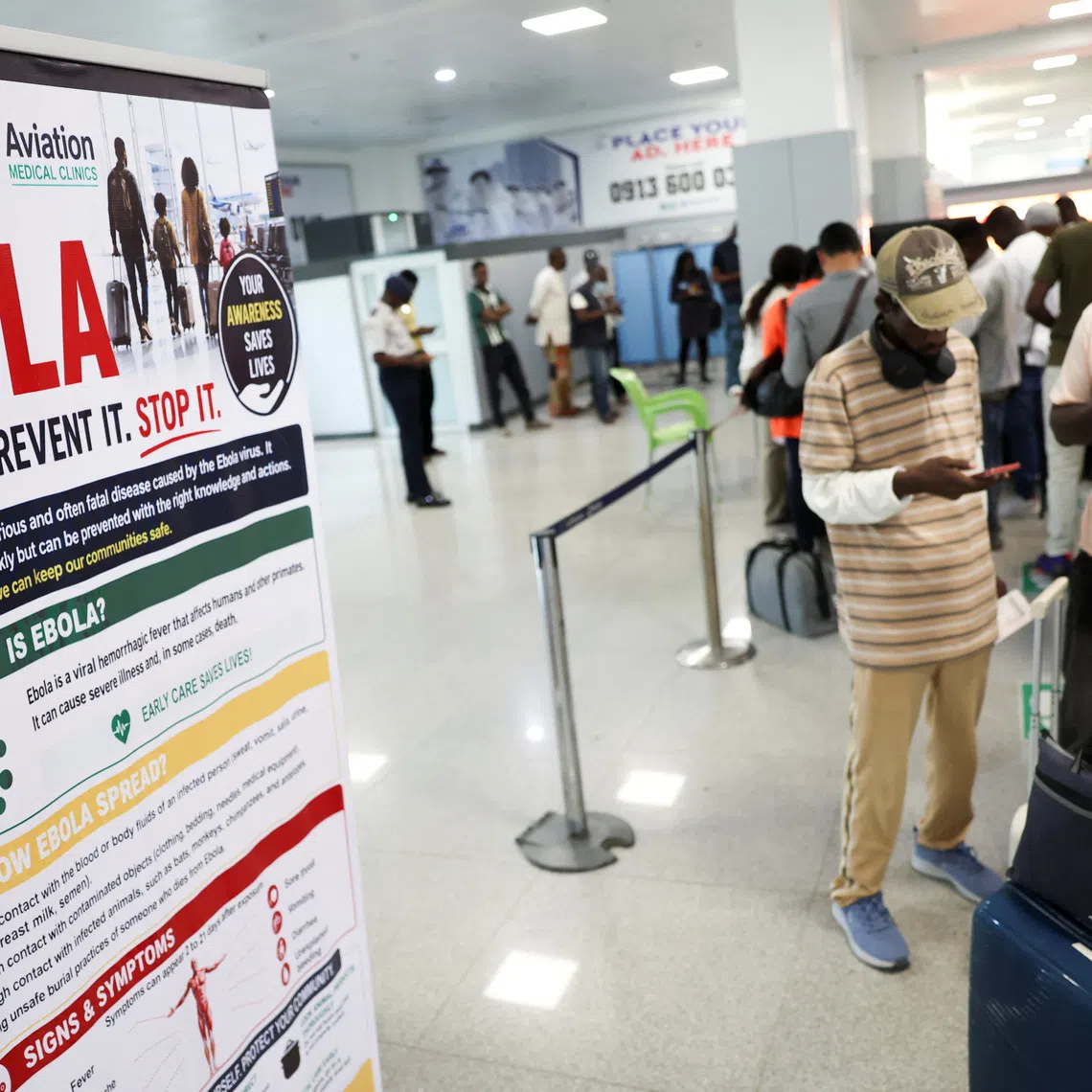 Travellers stand next to a banner displayed by a health screening station at Murtala Muhammed International Airport following reports of an Ebola case in Nigeria, in Lagos, Nigeria, October 22, 2026. REUTERS/Sodiq Adelakun