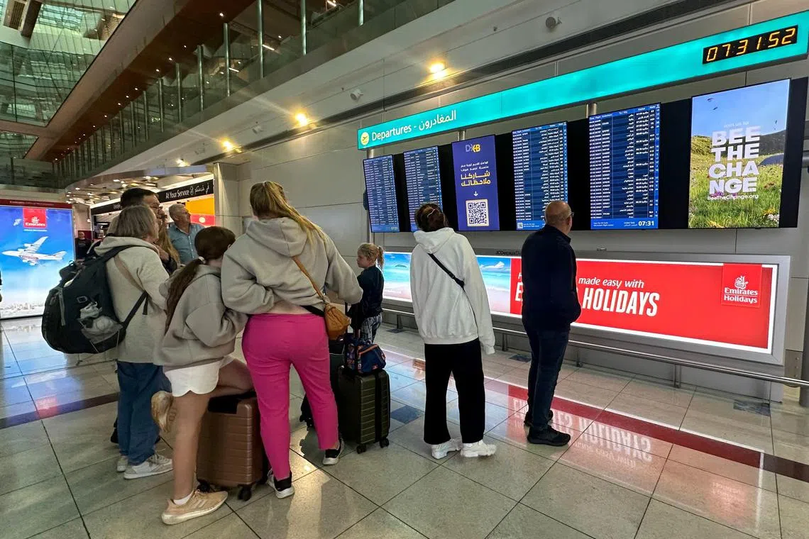 Passengers check flight information on screens at the Dubai International Airport in Dubai on April 17, 2024. Dubai's major international airport diverted scores of incoming flights on April 16 as heavy rains lashed the United Arab Emirates, causing widespread flooding around the desert country. Dubai, the Middle East's financial centre, has been paralysed by the torrential rain that caused floods across the UAE and Bahrain and left 18 dead in Oman on April 14 and 15. (Photo by AFP)