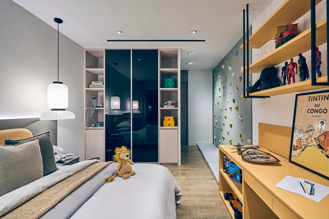 The second of the children’s bedrooms is lined with yellow shelves and a climbing wall.
