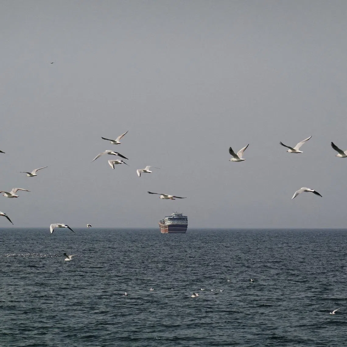 Birds fly near a boat in the Strait of Hormuz amid the U.S.-Israeli conflict with Iran, as seen from Musandam, Oman, March 2, 2026.REUTERS/Amr Alfiky