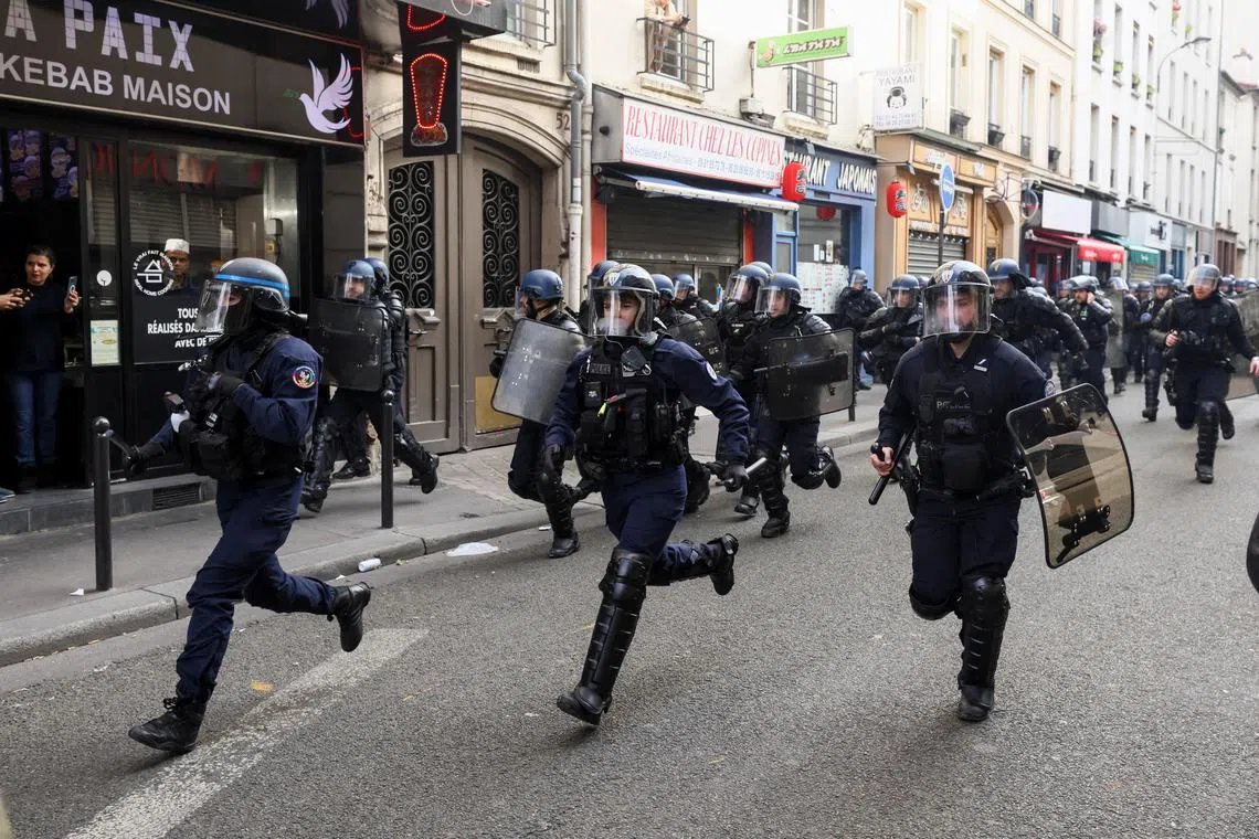 Police officers running during a demonstration against the French government's pension reform plan as part of the fourth day of national protests in Paris on Feb 11, 2023.