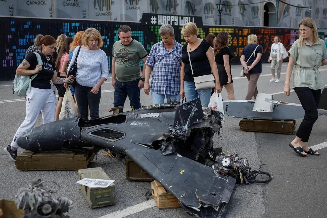 People checking out a destroyed Russian combat drone at an outdoor exhibition in central Kyiv.