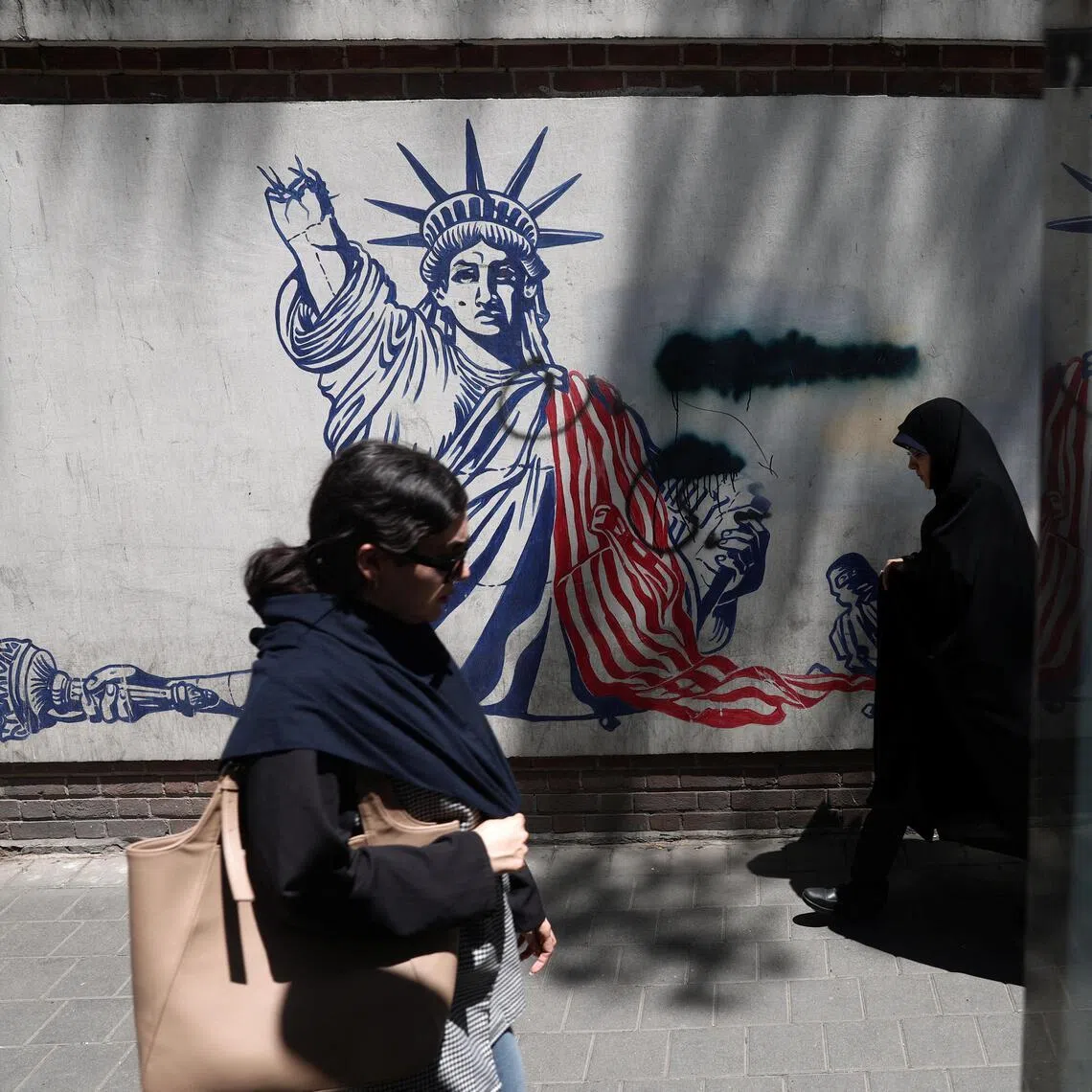 People walking past an anti-US mural on a street in Iran's capital, Tehran, on June 1.