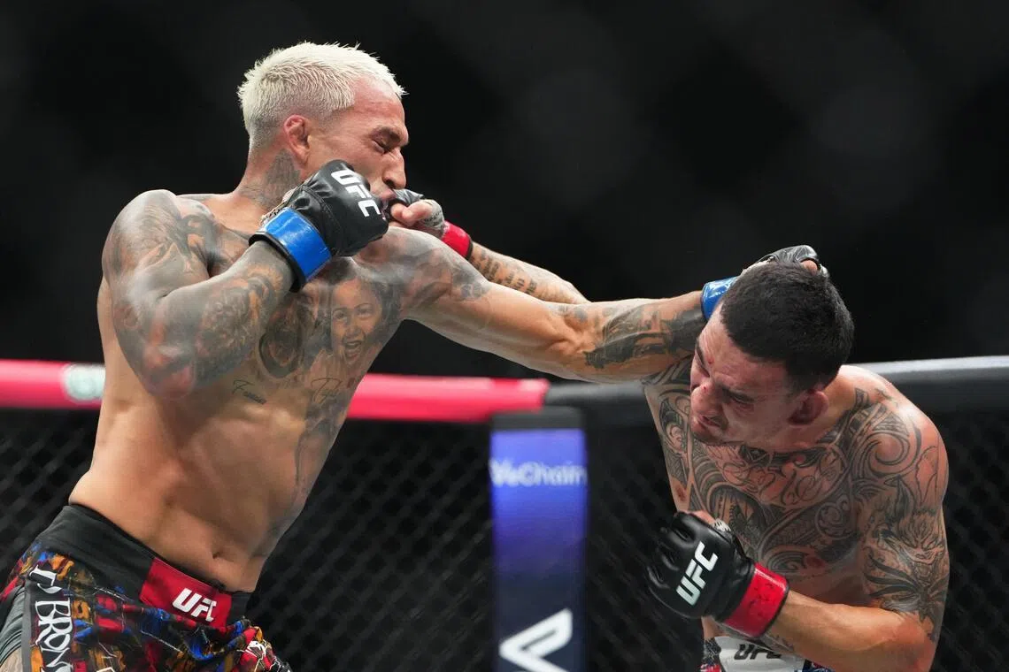 Max Holloway (red gloves) fights Charles Oliveira (blue gloves) during UFC 326 at T-Mobile Arena. 
