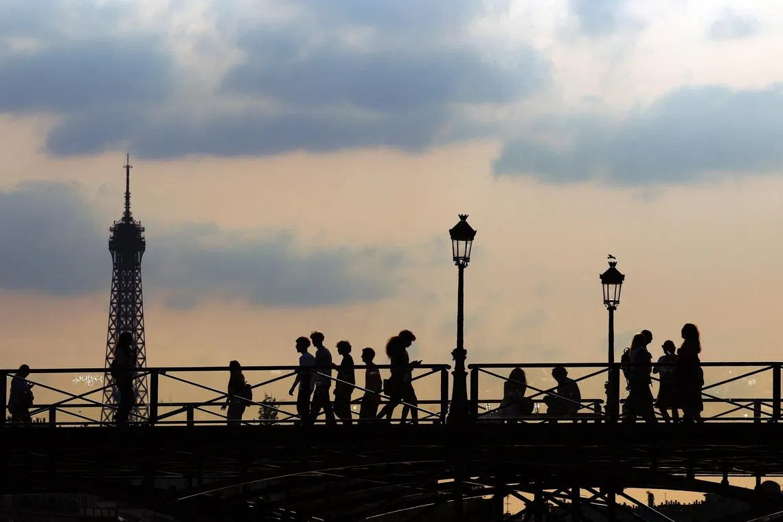 FILE PHOTO: People walk on the Pont de Arts bridge over the River Seine, with the Eiffel Tower in the background in Paris, France, May 2, 2025. REUTERS/Gonzalo Fuentes/File Photo