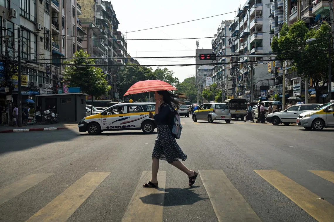 (FILES) A woman walks under an umbrella to shelter from the sun during a heatwave in Yangon on April 2, 2024. Myanmar recorded its hottest ever April temperature of 48.2 degrees Celsius (118.76 Fahrenheit), its weather department said on April 29, 2024, as the Southeast Asian nation bakes in a heatwave. (Photo by Sai Aung MAIN / AFP)
