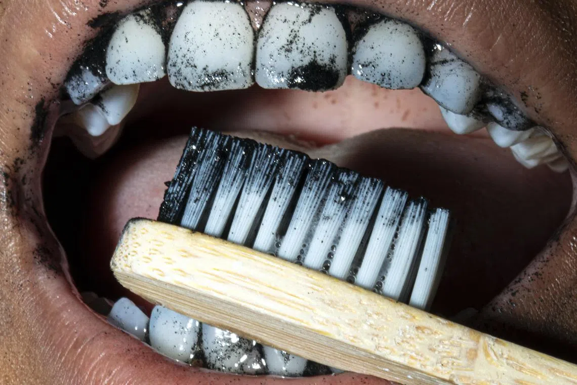 A person brushes their teeth in New York on July 10, 2024. Charcoal-infused brushes and toothpastes can be effective at whitening teeth, but the benefits come at a cost. 