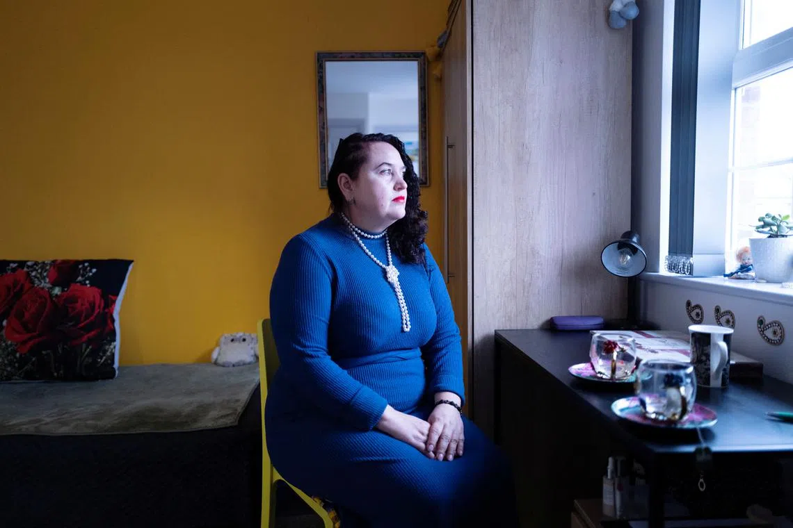 Ukrainian refugee Liudmyla (Mila) Panchenko looks out of a window while sitting on a chair at her current residence in Hatfield, Britain, February 21, 2024. REUTERS/Anna Gordon
