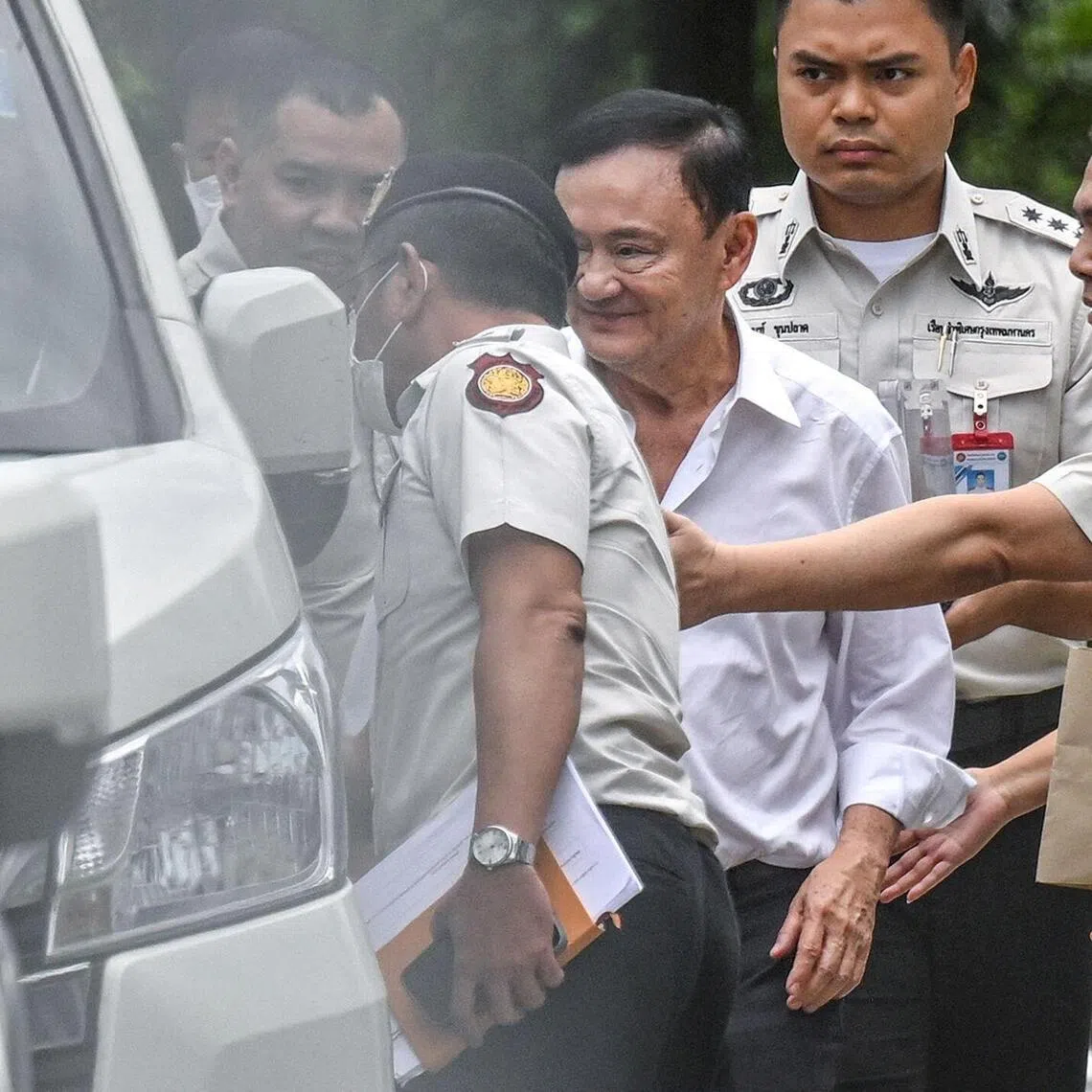 TOPSHOT - Thailand's former Prime Minister Thaksin Shinawatra (C) is escorted into a police van outside the Supreme Court in Bangkok on September 9, 2025, after he was sentenced to a year in prison. Thailand's Supreme Court ordered on September 9, that former prime minister Thaksin Shinawatra be taken to jail immediately to serve one year behind bars, after ruling his 2023 prison term was incorrectly served. (Photo by Panumas SANGUANWONG / THAI NEWS PIX / AFP)