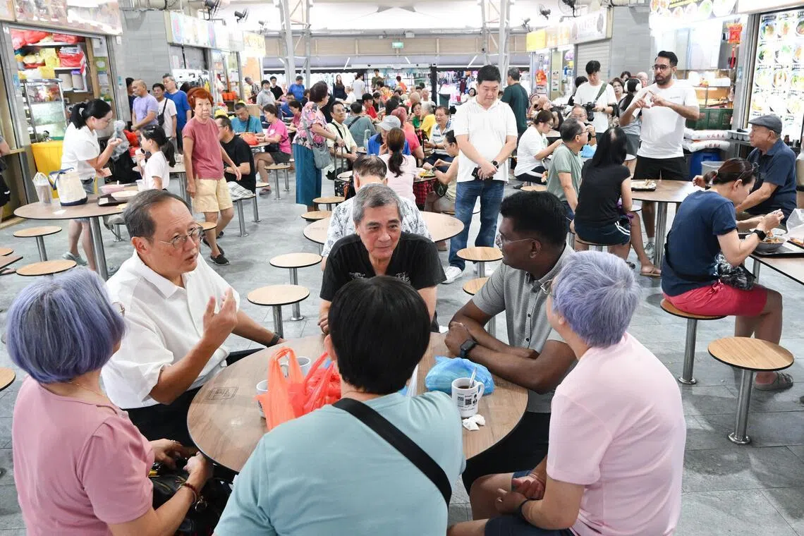 Manpower Minister Tan See Leng (second left, seated) met WP Secretary-General Pritam Singh (background, standing on the right), an Aljunied GRC MP, at 630 Bedok Reservoir Road Food Centre as they went on their walkabouts to greet residents.