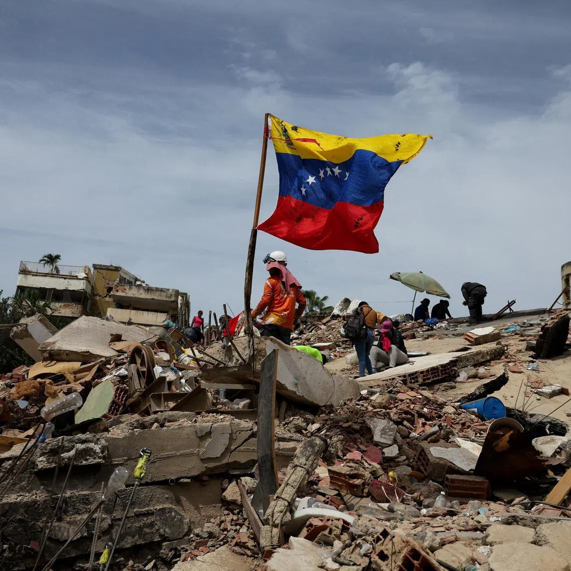 A flag of Venezuela flutters as rescuers work at the site of a collapsed building in the aftermath of the June 24 earthquakes, in La Guaira, Venezuela on July 5.