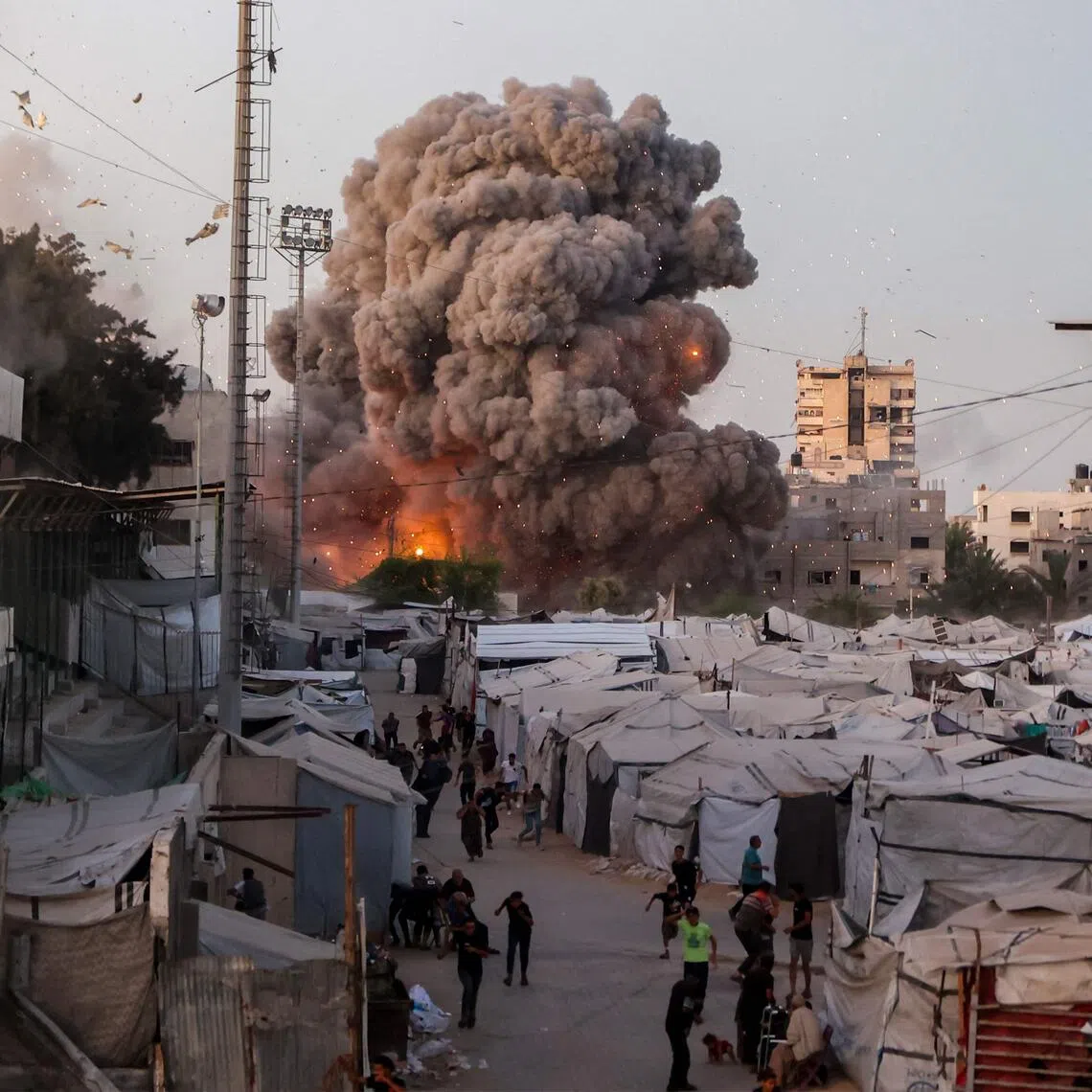 Palestinians run for cover as smoke and fire rise during an Israeli strike on the the Al-Muttaqin Mosque in Gaza City on July 28.