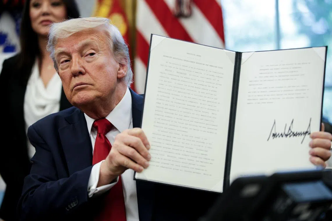US President Donald Trump displays a signed executive order in the Oval Office of the White House on April 23, 2025. 