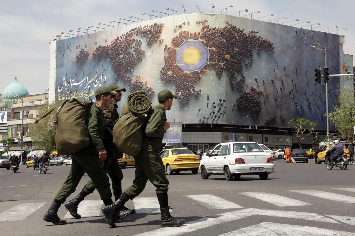 epa12017450 Iranian soldiers walk next to a huge banner carrying a sentence reading in Persian 'Stay steadfast on this path' in a street, in Tehran, Iran, 08 April 2025. Iranian Foreign Minister Abbas Araqchi said on 08 April that top Iranian and US officials will hold indirect negotiations in Oman on 12 April.  EPA-EFE/ABEDIN TAHERKENAREH