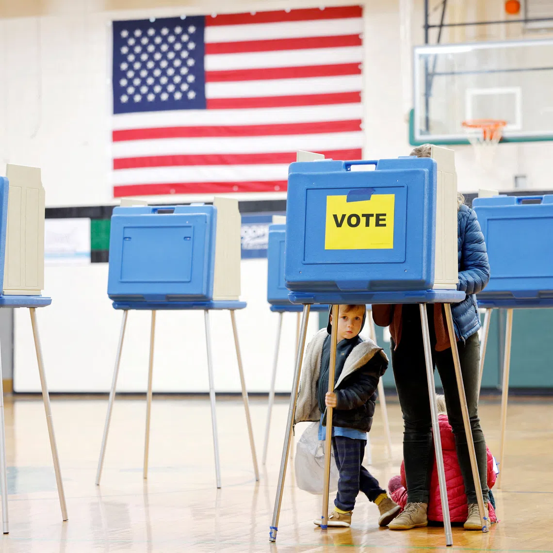 FILE PHOTO: A boy peers out from under a voting booth as his mother marks her ballot during the state’s primary election to choose candidates for the November midterm elections, in Cary, North Carolina, U.S., March 3, 2026.  REUTERS/Jonathan Drake/File Photo