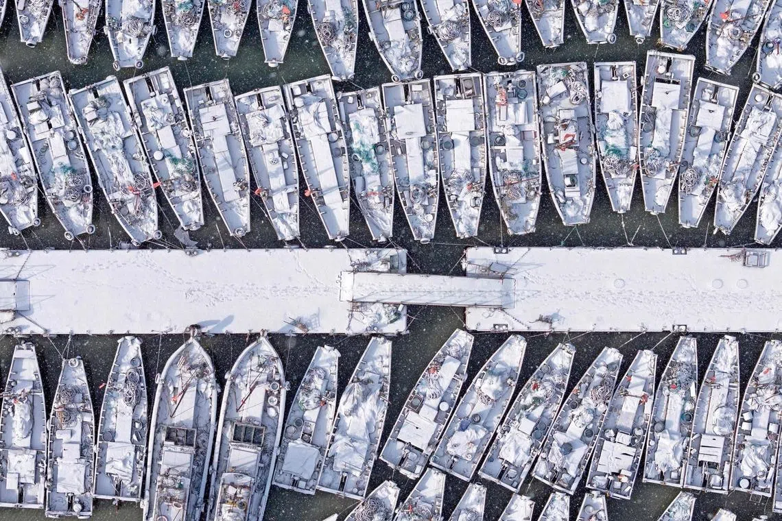 An aerial view of snow-covered fishing boats moored at the Dongkou Fishing Port in Yantai, in China's eastern Shandong province on Jan 21, 2026. 