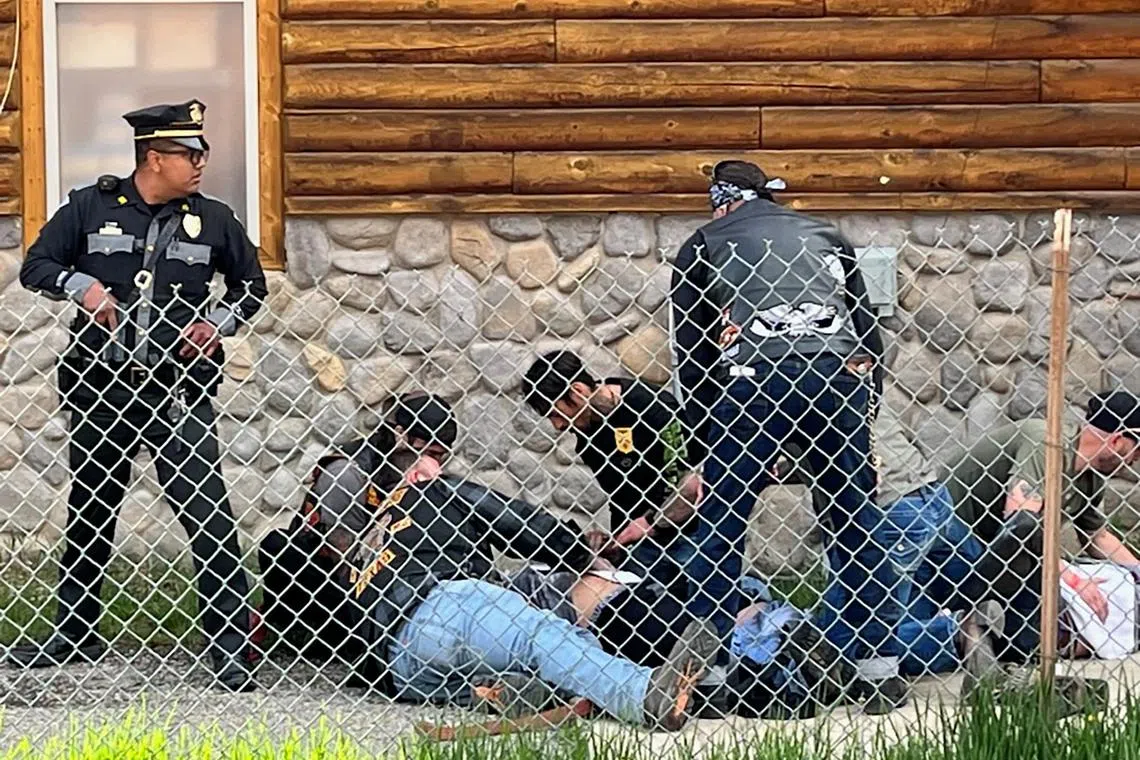 A police officer stands guard as man with a Bandidos MC patch assists a shot biker in Red River, New Mexico.