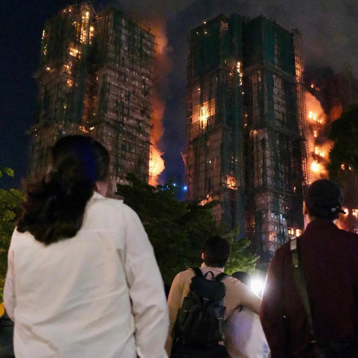 People look on as thick smoke and flames rise during a major fire at the Wang Fuk Court residential estate in Hong Kong's Tai Po district on Nov 26, 2025.