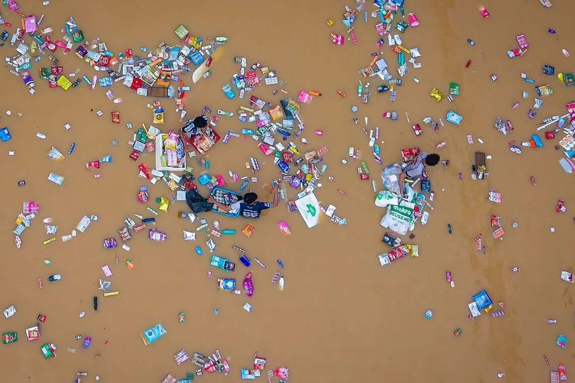 People surrounded by floating products from a supermarket as they wade through flood waters in Hat Yai in Thailand's southern Songkhla province, as severe flooding affected thousands of people in the country's south following days of heavy rain, Nov 26, 2025. 