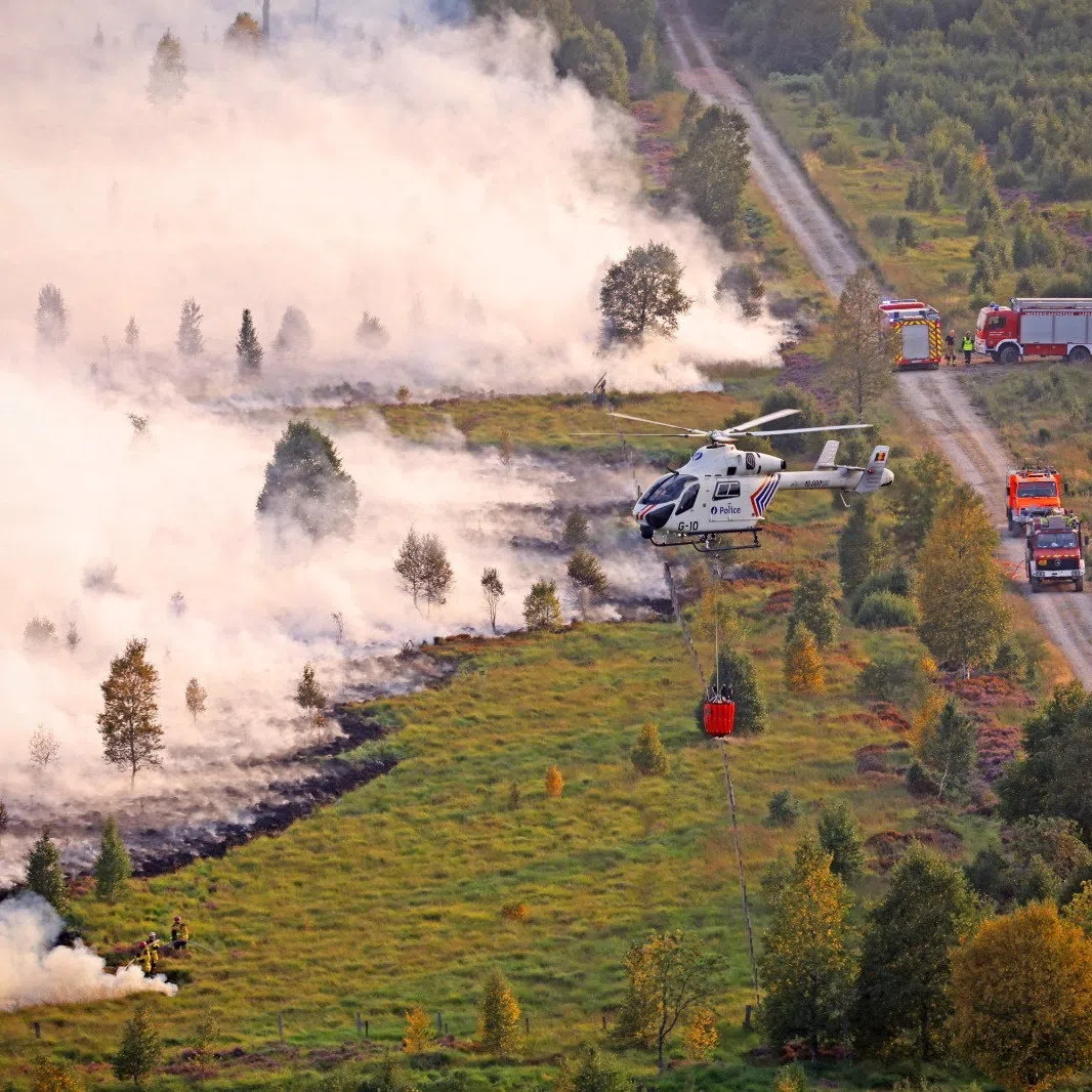 Fire services personnel are deployed as smoke rises from a wildfire, in the High Fens region of Belgium, on Aug 17.