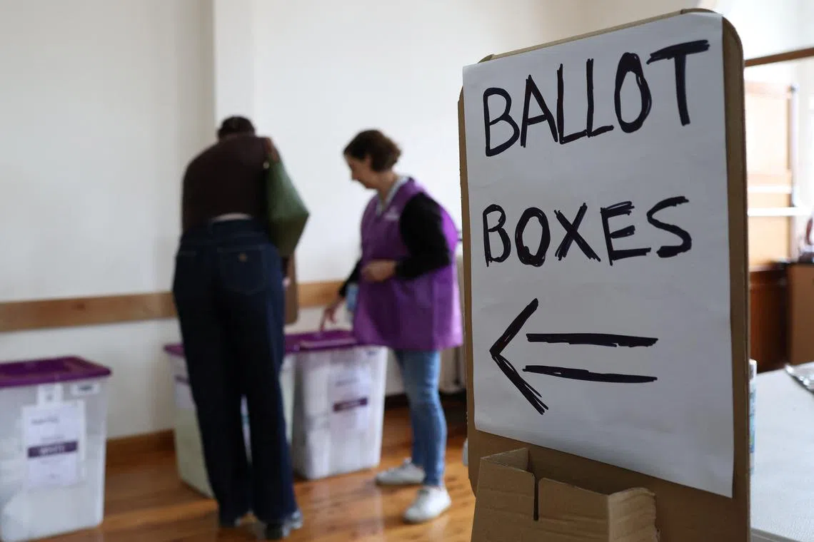 FILE PHOTO: A sign points towards ballot boxes at a pre-polling place in Sydney, Australia, April 30, 2025. REUTERS/Hollie Adams/File Photo