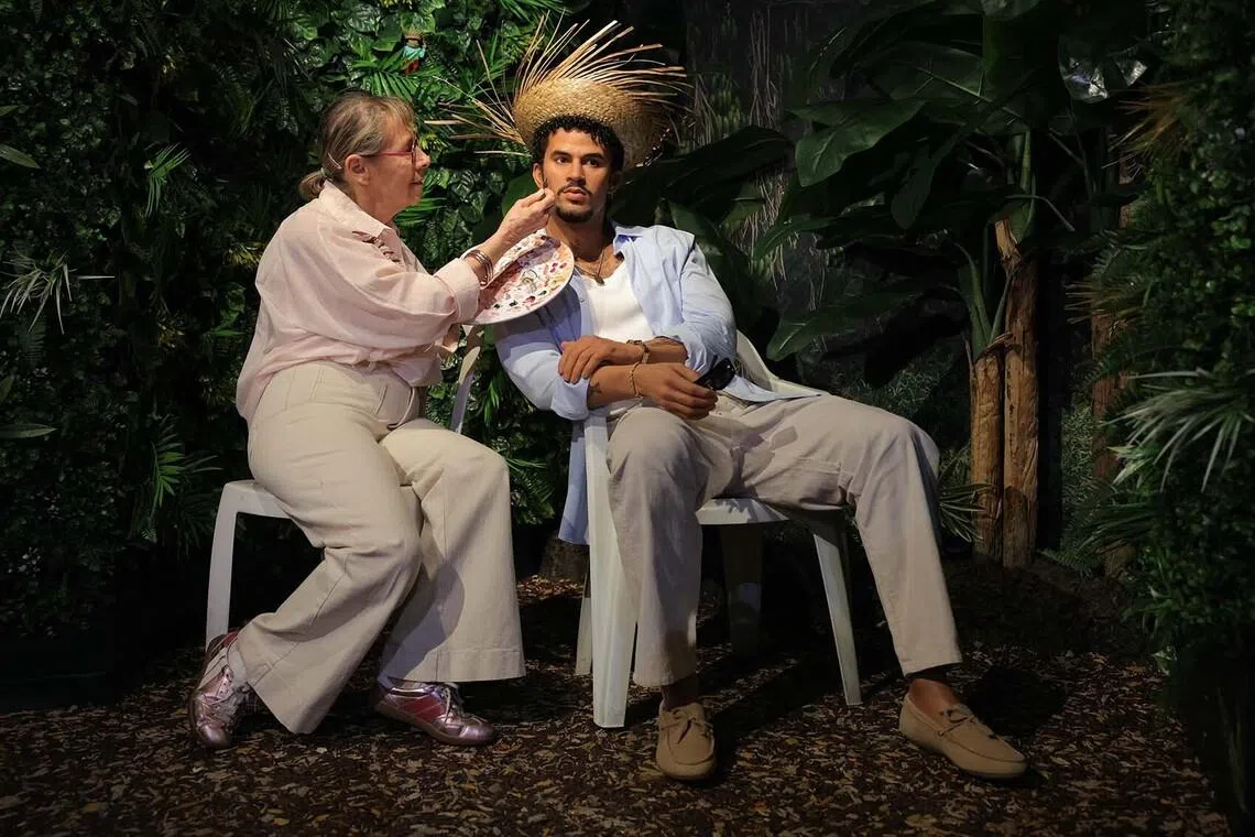 TOPSHOT - An employee paints the wax effigy of Puerto Rican singer Bad Bunny during its unveiling at the Musee Grevin in Paris on July 1, 2026. (Photo by Thomas SAMSON / AFP)