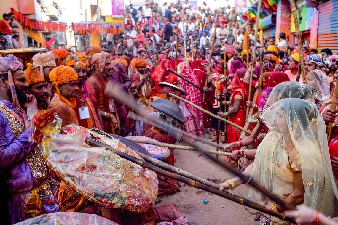 Women playfully hitting revellers with sticks as a traditional ritual during the Lathmar Holi celebrations, the Hindu spring festival of colours, in Barsana, in India's northern state of Uttar Pradesh on March 8, 2025. 