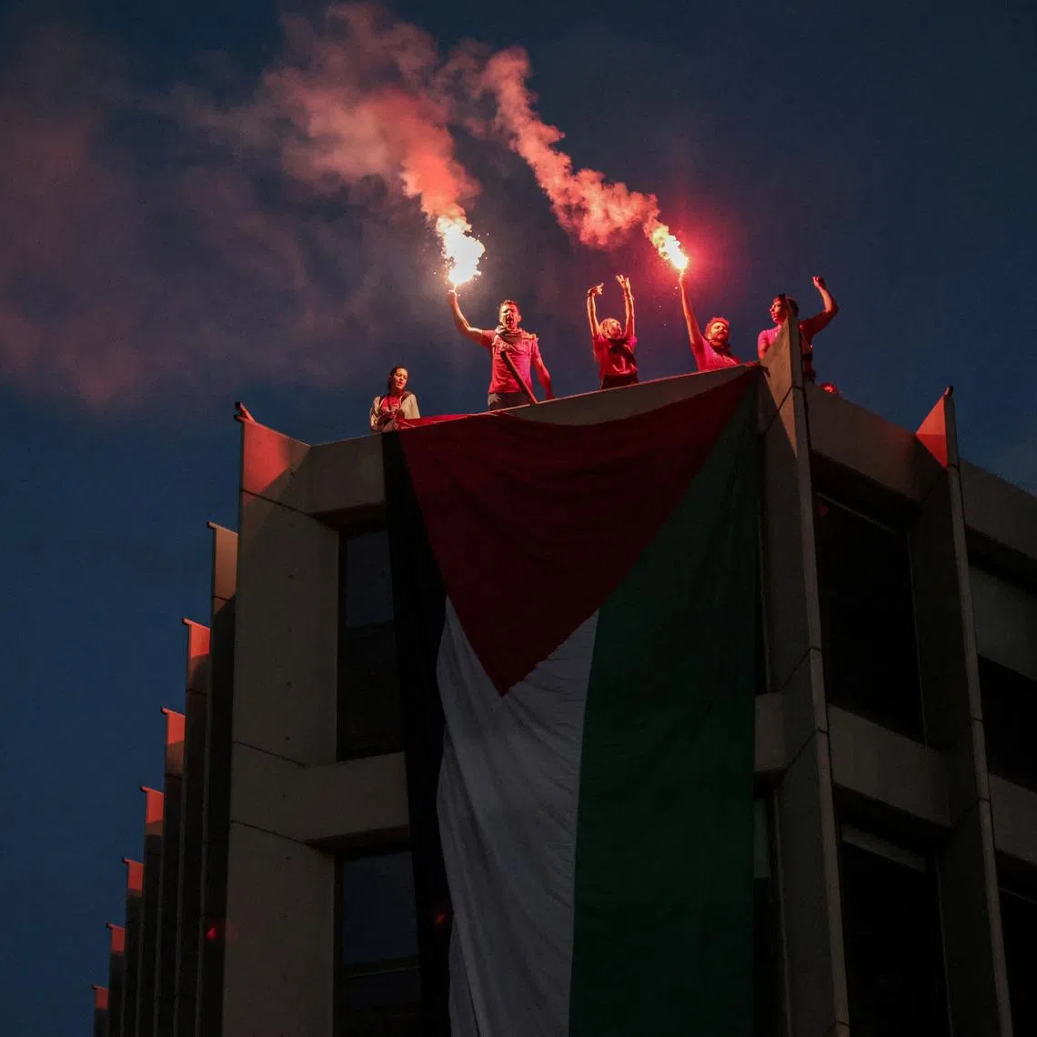 Protesters who hung a huge Palestinian flag at a building facing the Israeli embassy, lit flares during a protest over the interception of the Gaza aid flotilla, in Athens, Greece, May 21, 2026. REUTERS/Louisa Gouliamaki