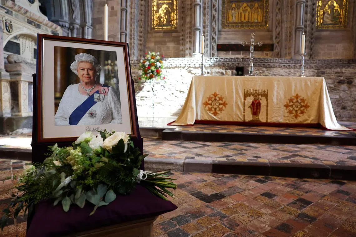 Flowers placed by Britain's Prince William and his wife, Catherine, are pictured next to a portrait of the late Queen Elizabeth II, at St David's Cathedral in Wales.