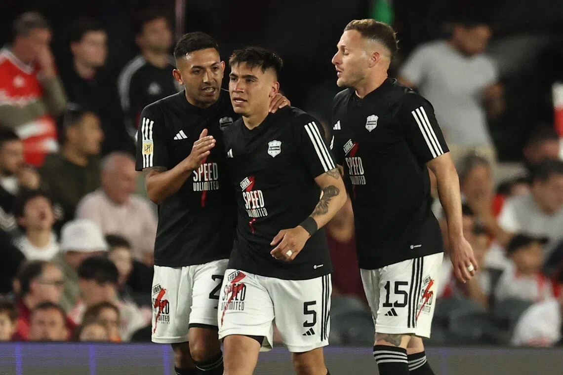 Deportivo Riestra defender Pedro Ramirez (centre) celebrates with defender Jonatan Goitia (left) and defender Nicolas Sansotre, after scoring his team's second goal in the Argentine Professional Football League 2025 Clausura Tournament match against River Plate at the Mas Monumental Stadium in Buenos Aires, on Sept 28, 2025.