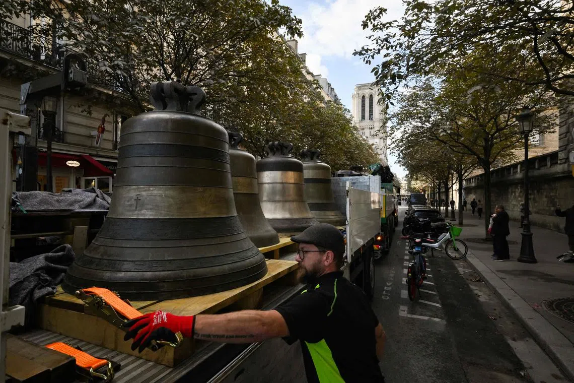 A worker stands near the eight bells that have been cleaned of lead dust thrown off by a burning roof as the Notre Dame cathedral burned in 2019.