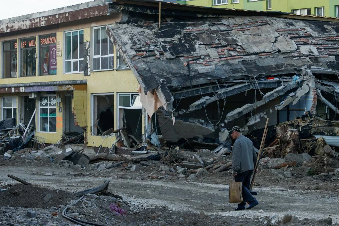 FILE PHOTO: A man with a broom walks by a destroyed building days after intensive flooding in Stronie Slaskie, Poland, September 20, 2024. REUTERS/Kuba Stezycki/File Photo