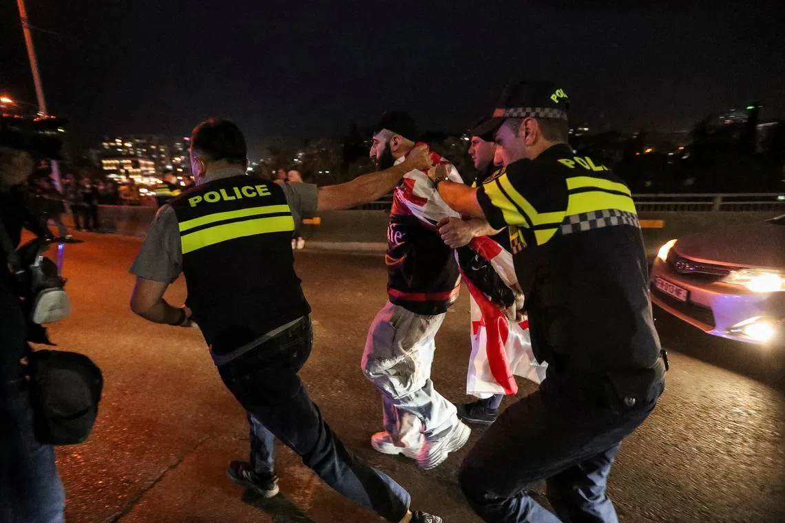 Police officers lead a demonstrator away as people hold a rally to protest against a bill on \"foreign agents\" in Tbilisi, Georgia, May 2, 2024. REUTERS/Irakli Gedenidze/File photo