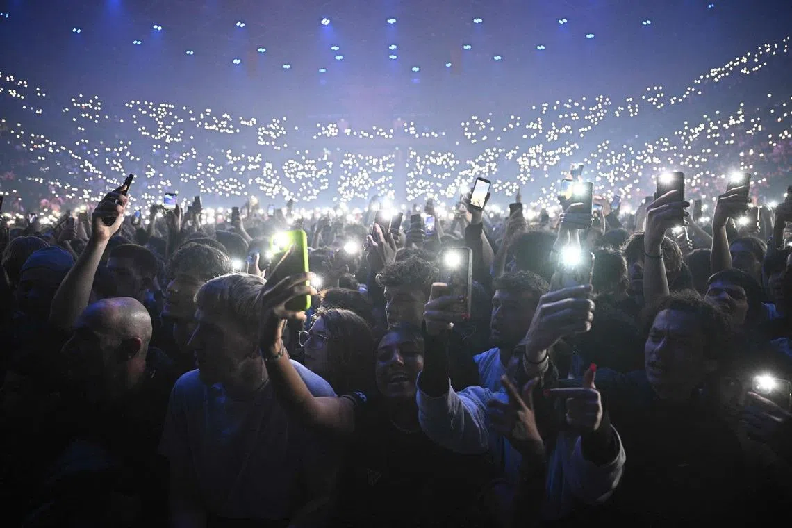 Fans holding smartphones with activated flashes during a concert in tribute to French late rapper Werenoi at the Accor Arena in Paris, France on March 25, 2026. 