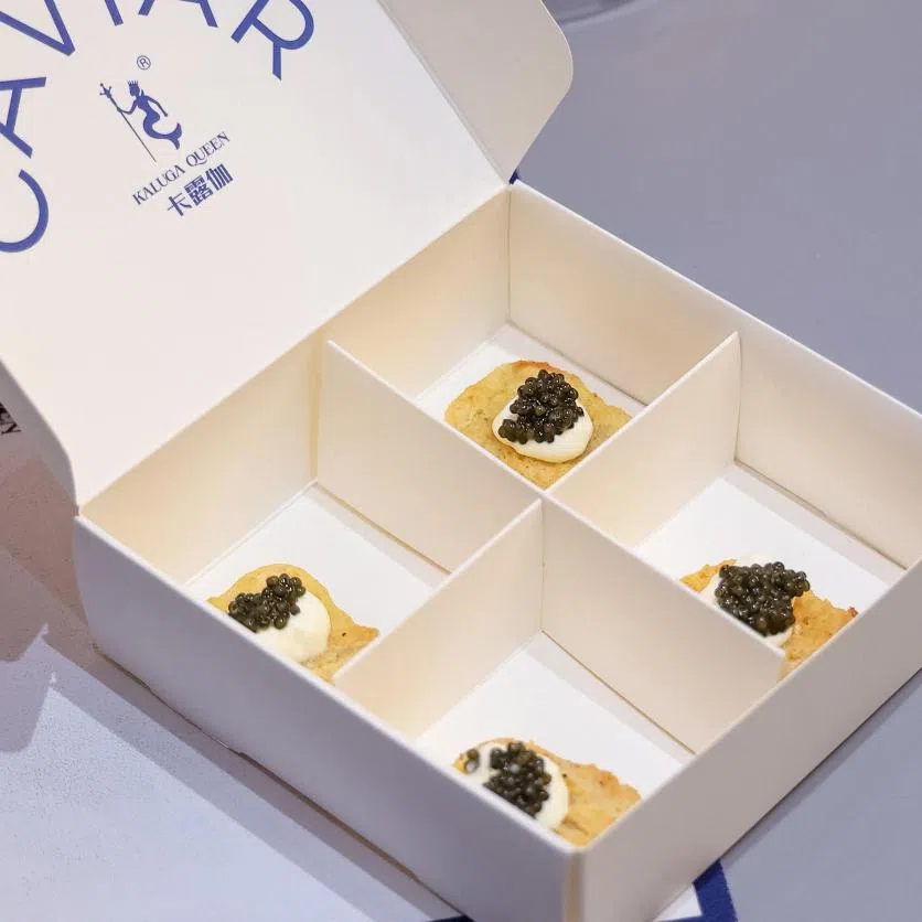 A grown sturgeon in Kaluga Queen’s land farm in Quzhou and chicken nuggets topped with caviar, one of the snacks you can try at Kaluga Queen’s experience store in Quzhou.