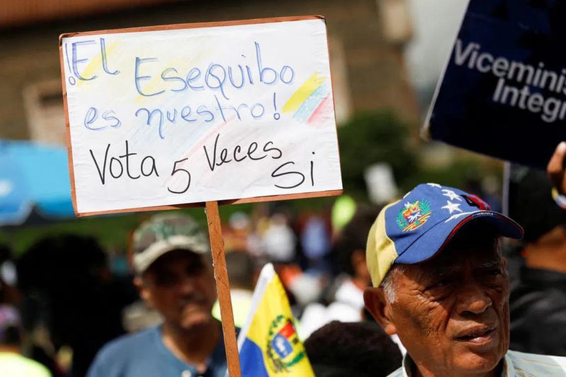 FILE PHOTO: A government supporter holds a sign that reads: “The Essequibo is ours, vote YES 5 times” while participating in an event to collect signatures in support of a referendum over Venezuela's rights to the potentially oil-rich region of Esequiba in Guyana, in Caracas, Venezuela November 15, 2023. REUTERS/Leonardo Fernandez Viloria/File Photo
