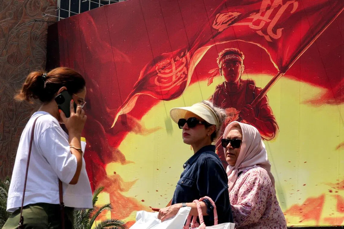 Women walking past a political billboard in central Tehran on Aug 8.