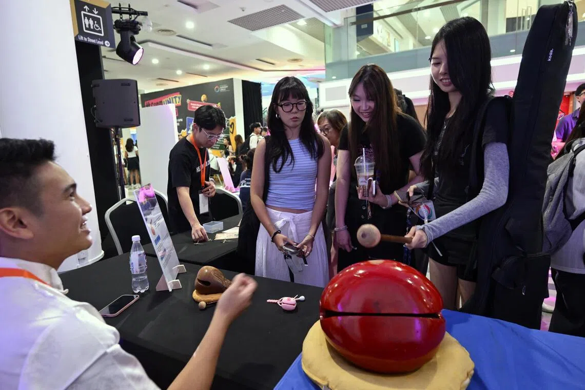 Representative from Singapore Taoist Federation, Edmund Zhang (left), 36, shares information about the wooden fish, a ritual percussion instrument in both Taoism and Buddhism to SMU students, (L-R) Lyneth Ser, 21, Etienne Wong, 21 and Lorraine Lim, 20 at #commUNITY on Campus held in SMU on Sept 18, 2026.
