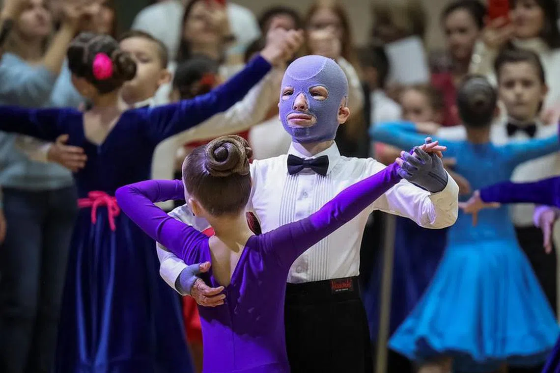 Roman, 8, wounded by Russian missile strike on the central Ukrainian city of Vinnytsia last year, performs at a ballroom dance competition, with his face covered by a burn mask, after a year of skin grafts and over 30 surgeries, in Lviv, Ukraine December 2, 2023.  REUTERS/Roman Baluk/File Photo