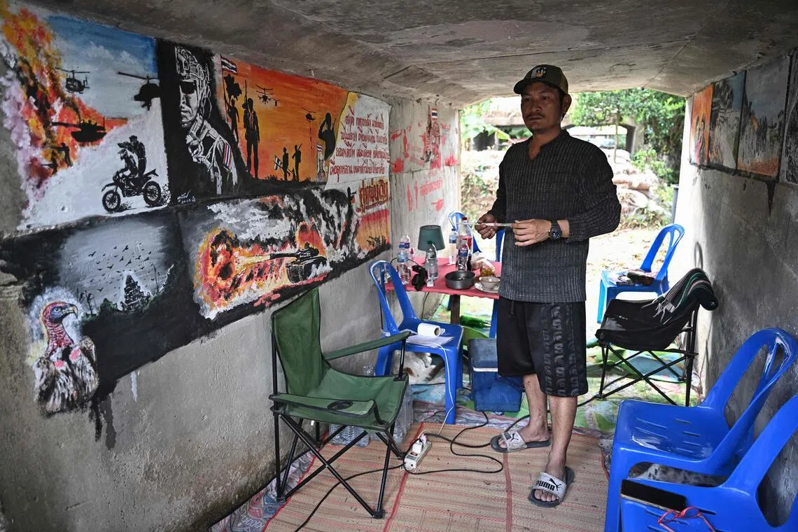 Thai teacher Watthanachai Kamngam with murals depicting the border conflict he painted in a bunker near his home in Surin.