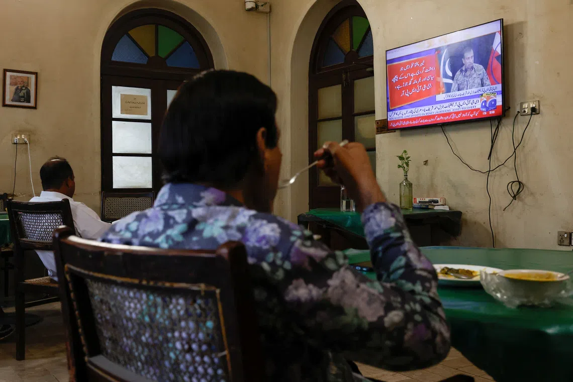 People watch a televised press briefing by Ahmed Sharif Chaudhry, Director General of the Inter-Services Public Relations wing of the Pakistan Armed Forces, in Karachi, Pakistan, October 10, 2025. REUTERS/Akhtar Soomro