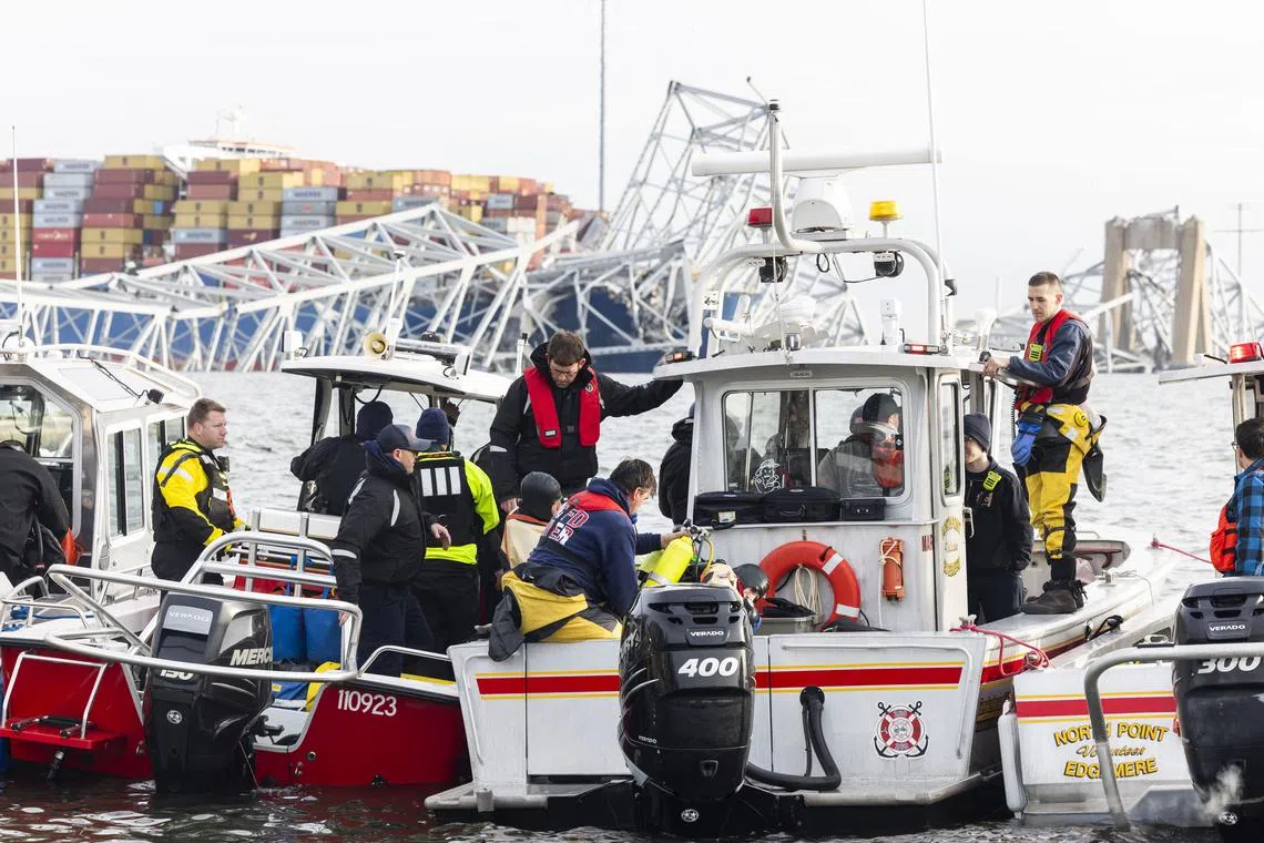 Rescue personnel heading out on the Patapsco River after a container ship ran into the Francis Scott Key Bridge (back) causing its collapse in Baltimore, Maryland, March 26, 2024. 