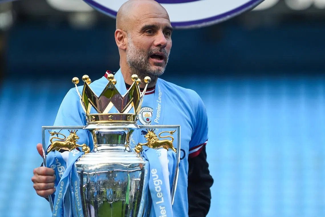 Manchester City manager Pep Guardiola celebrates with the trophy after winning the Premier League.