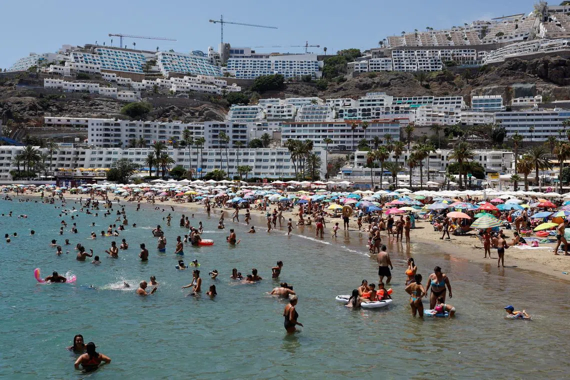 FILE PHOTO: Tourists bathe and sunbathe on the beach of Puerto Rico in the south of the island of Gran Canaria, Spain, August 6, 2023. REUTERS/Borja Suarez/File Photo