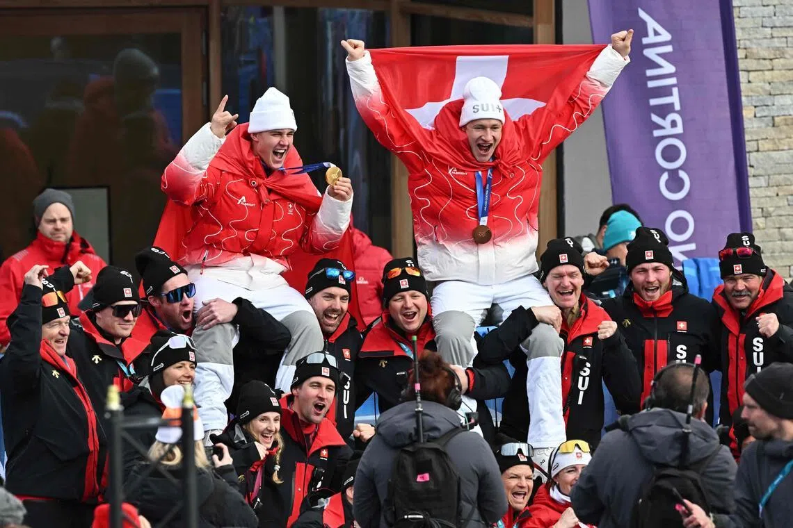 Gold medallist Franjo von Allmen (left) and bronze medallist Marco Odermatt, both of Switzerland, celebrating with team members after the men's super-G alpine skiing event during the 2026 Milano- Cortina Winter Olympic Games at the Stelvio Ski Centre in Bormio on Feb 11, 2026.