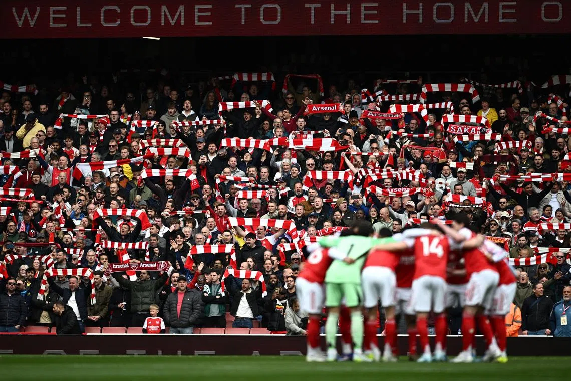 Soccer Football - Premier League - Arsenal v AFC Bournemouth - Emirates Stadium, London, Britain - April 11, 2026 Arsenal fans holds scarves up inside the stadium as Arsenal players huddle before the match REUTERS/Dylan Martinez