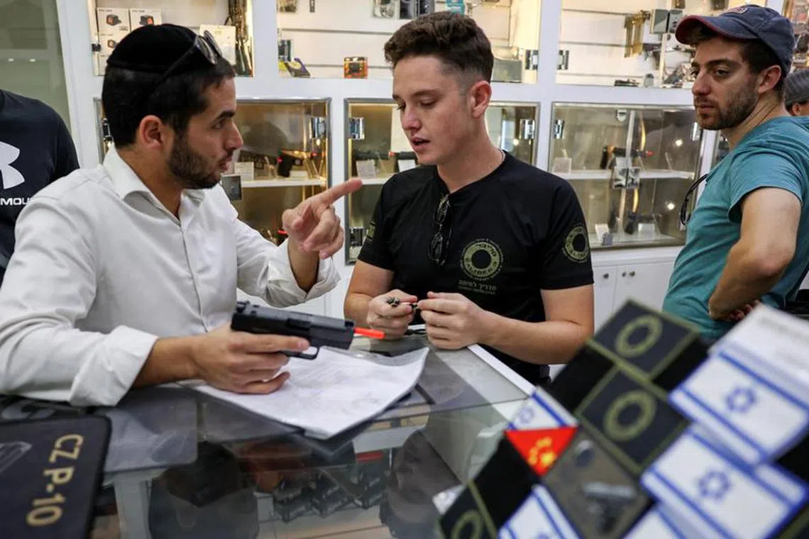 A customer speaks to a member of staff at a gun shop at the Caliber 3 shooting range in Gush Etzion, an Israeli settlement in the Israeli-occupied West Bank, on October 25, 2023. REUTERS/Ronen Zvulun