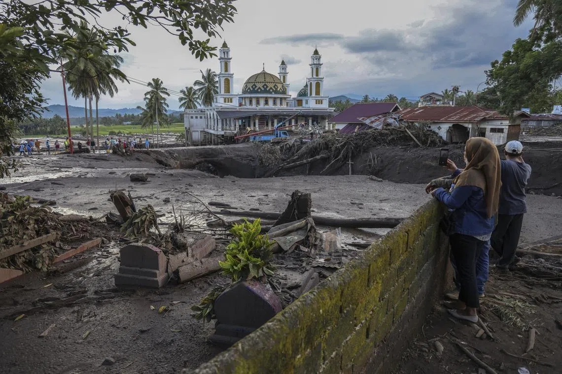 epaselect epa11335096 People look at a flood affected area following a flash flood in Tanah Datar, West Sumatra, Indonesia, 12 May 2024. At least 28 people were killed after heavy rain triggered flash floods and cold lava flow from Marapi volcano hitting villages in Tanah Datar and Agam Regency, West Sumatra province, according to the National Board for Disaster Management (BNPB).  EPA-EFE/GIVO ALPUTRA