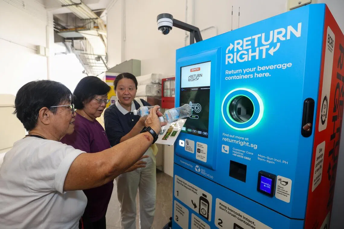A BCRS representative guiding Canberra residents in returning their empty drinks bottles at a BCRS machine at Block 313 Sembawang Drive on Jun 6.